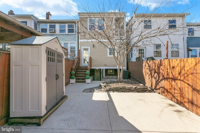 exterior space with a fenced backyard, an outdoor structure, a patio, and a shed