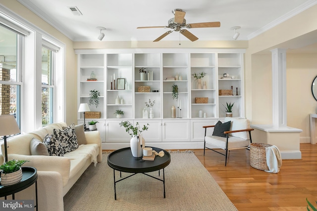 sitting room featuring light wood-style flooring, visible vents, a ceiling fan, ornamental molding, and decorative columns