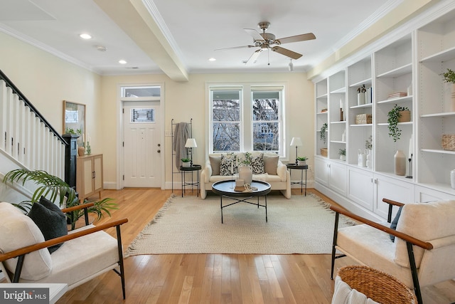 sitting room with light wood-style floors, stairs, and crown molding