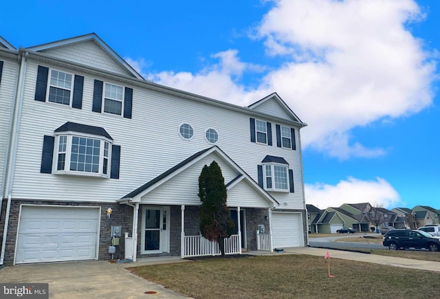 view of property with a porch, concrete driveway, a front yard, a garage, and stone siding