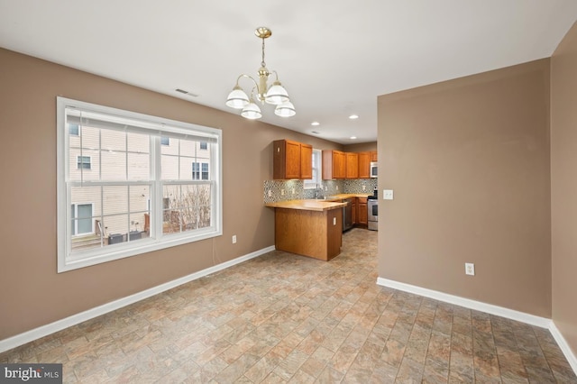 kitchen with appliances with stainless steel finishes, brown cabinets, baseboards, and decorative backsplash