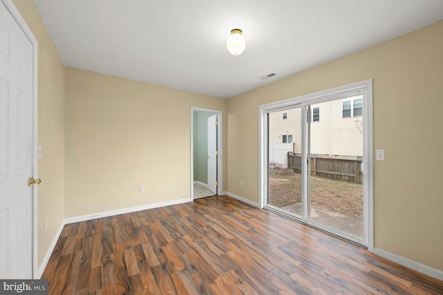 unfurnished bedroom with wood finished floors, visible vents, and baseboards