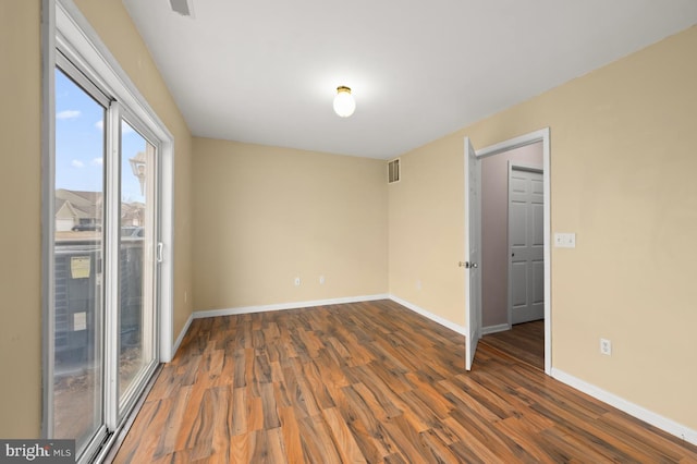 empty room with visible vents, baseboards, and wood finished floors