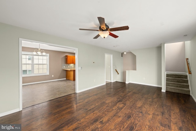 unfurnished living room with dark wood-style floors, ceiling fan with notable chandelier, baseboards, and stairs