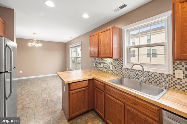 kitchen with butcher block counters, visible vents, stainless steel appliances, and a sink