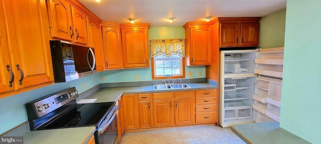 kitchen with stainless steel appliances, brown cabinets, and a sink