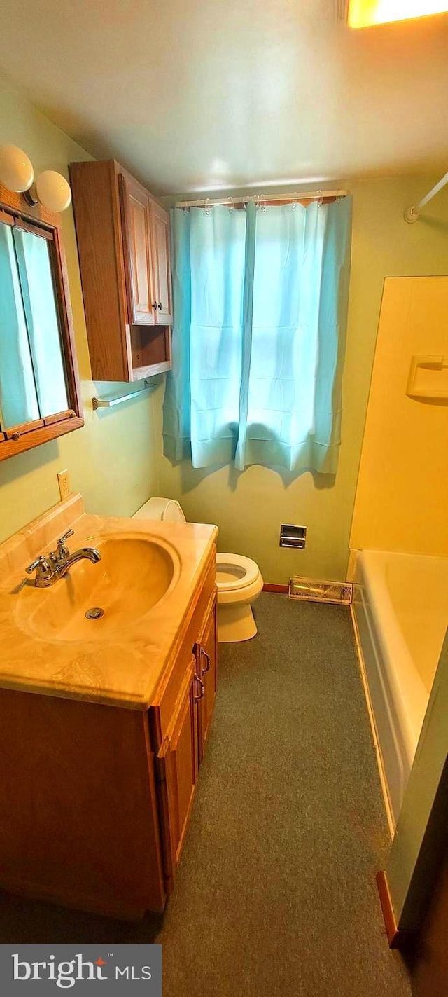 bathroom with washtub / shower combination, vanity, and toilet