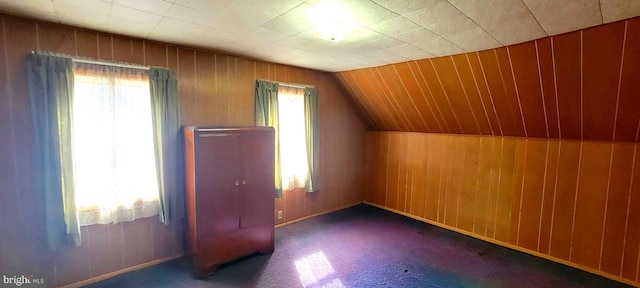 bonus room featuring lofted ceiling, plenty of natural light, wooden walls, and carpet