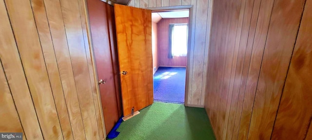 hallway with carpet floors and wood walls