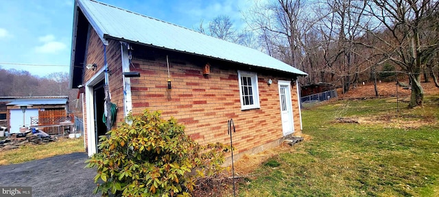 view of side of property featuring a yard, brick siding, and metal roof