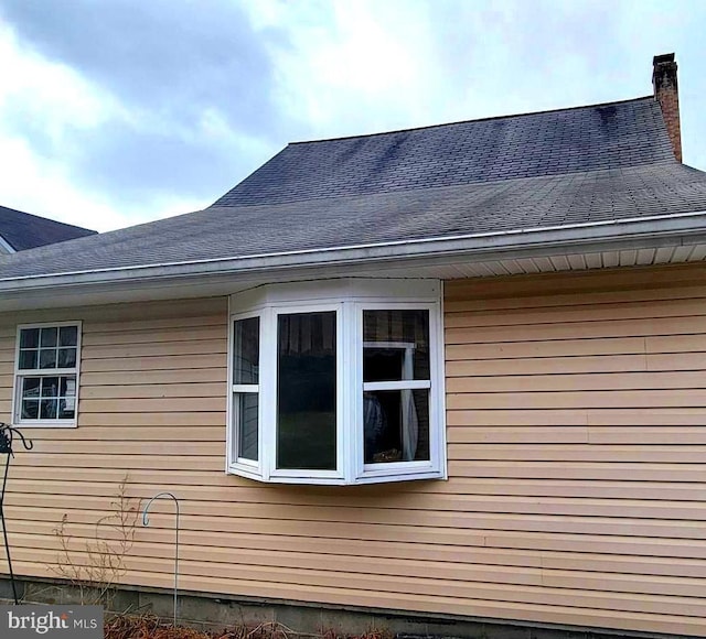 view of home's exterior with a shingled roof and a chimney