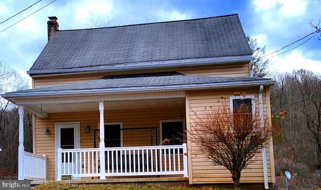 exterior space featuring a porch, roof with shingles, and a chimney