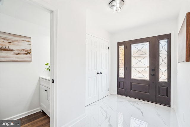 foyer entrance with baseboards and marble finish floor