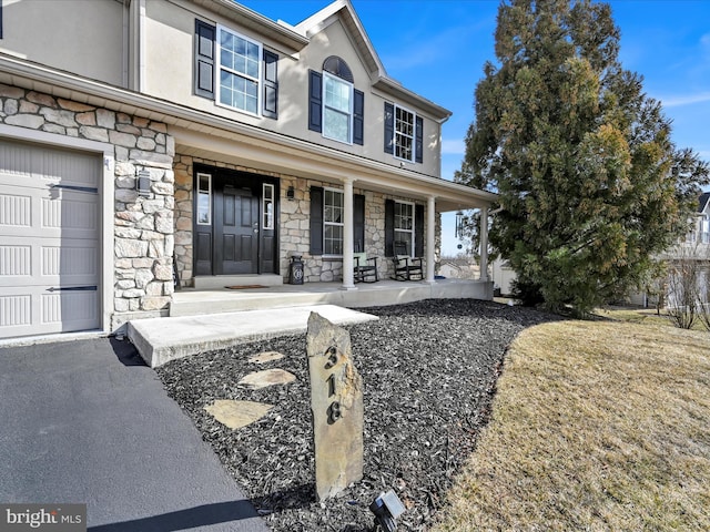 view of front of house with stone siding, a porch, and stucco siding