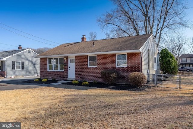 ranch-style home with a chimney, a gate, fence, a front lawn, and brick siding