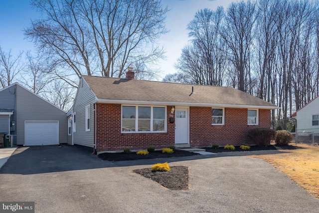 ranch-style house featuring brick siding, a chimney, an outdoor structure, and aphalt driveway