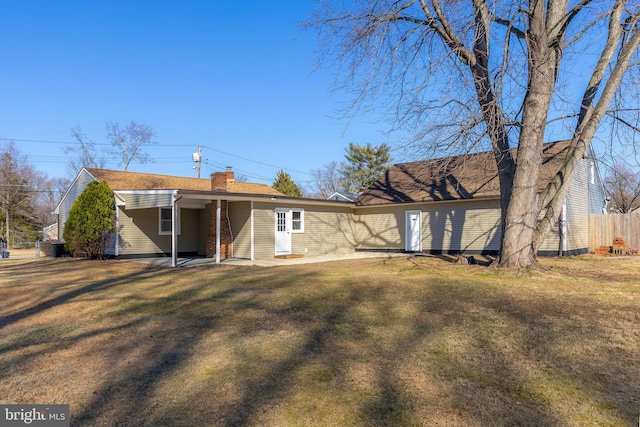 back of house with a chimney, fence, and a lawn