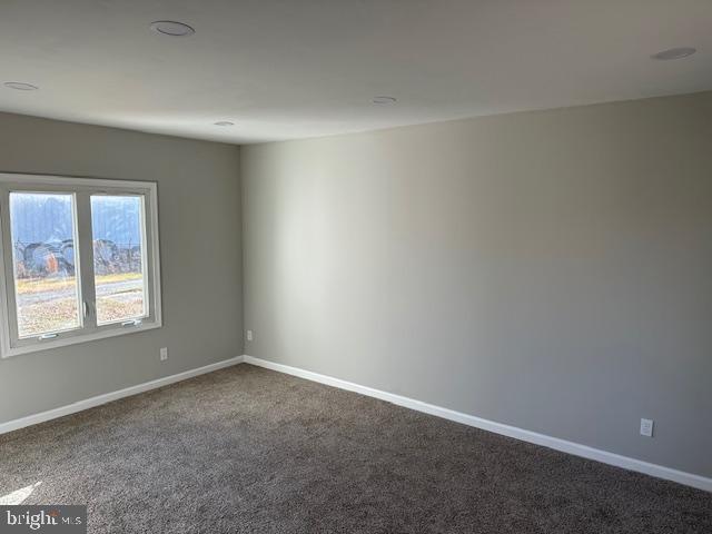 empty room featuring dark carpet and baseboards