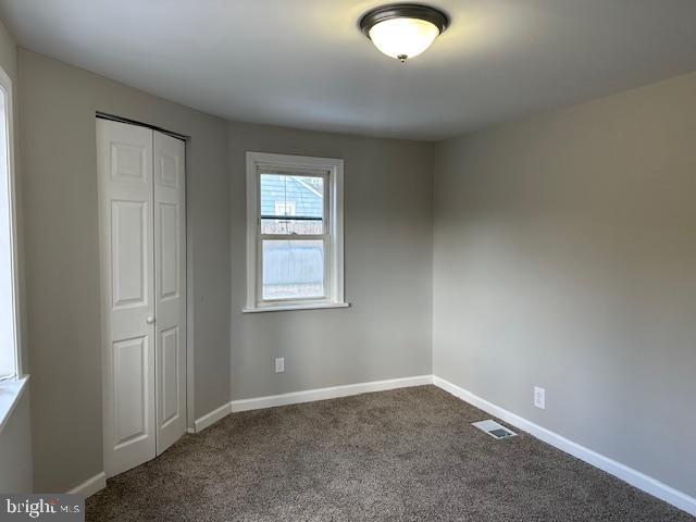 unfurnished bedroom featuring a closet, carpet flooring, visible vents, and baseboards