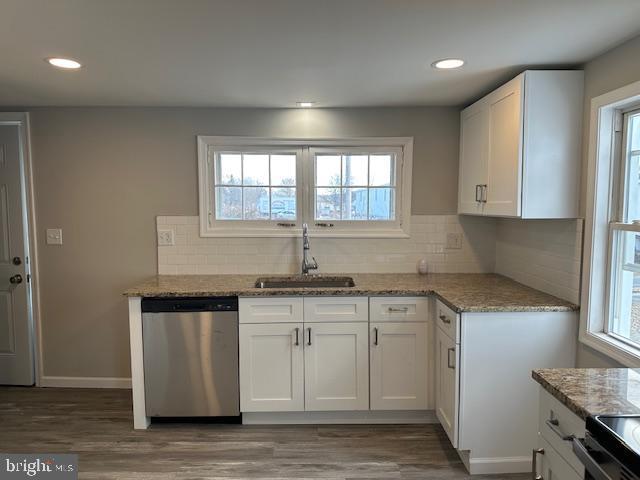 kitchen featuring tasteful backsplash, dishwasher, light stone counters, white cabinetry, and a sink