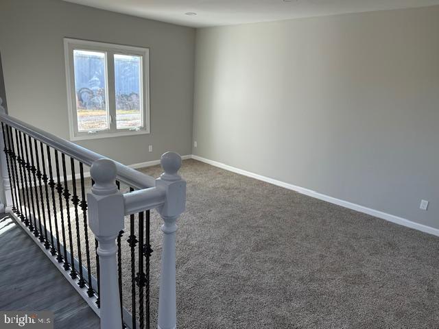 interior space featuring baseboards and dark carpet