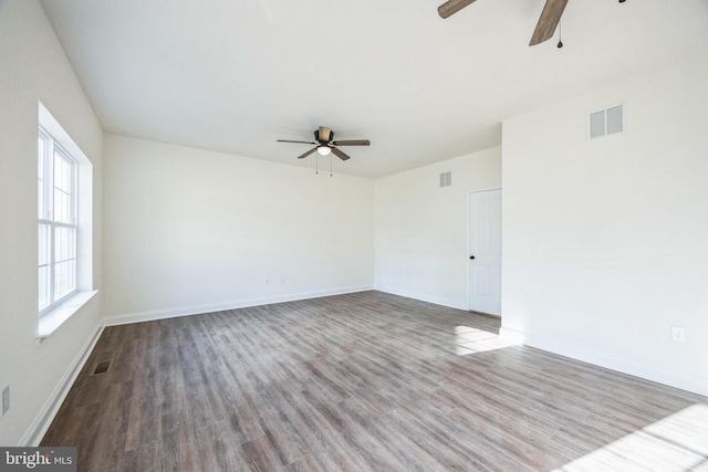 empty room with baseboards, visible vents, and wood finished floors