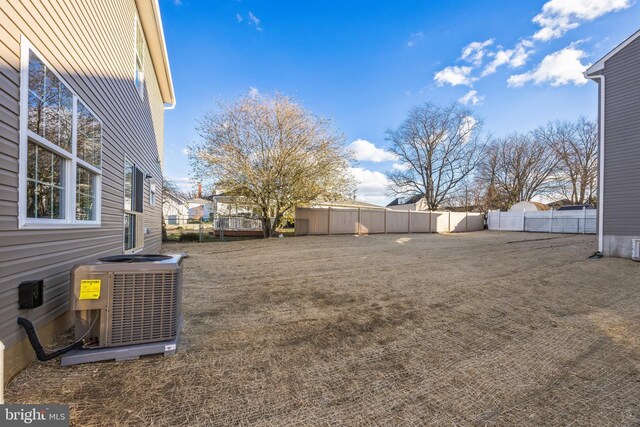 view of yard featuring central AC and fence