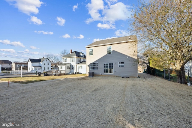 back of property featuring driveway, fence, and central AC unit