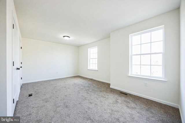 unfurnished room featuring carpet, visible vents, and baseboards