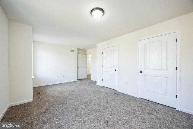 unfurnished bedroom featuring multiple closets, carpet flooring, and baseboards