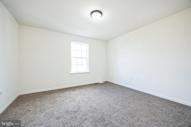 spare room featuring carpet floors and baseboards