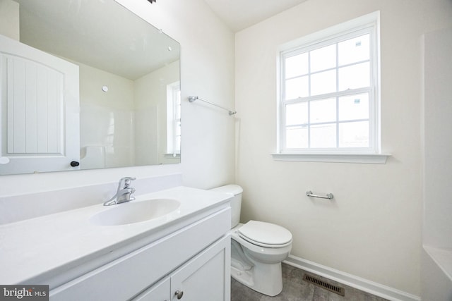 bathroom with toilet, vanity, visible vents, baseboards, and a shower