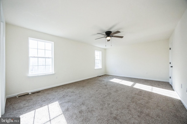 spare room featuring carpet flooring, ceiling fan, visible vents, and baseboards