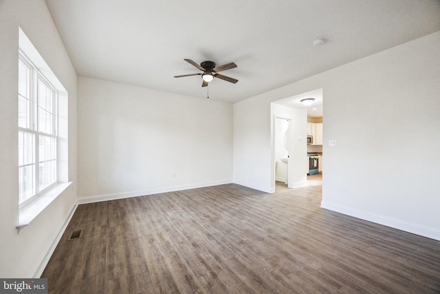 unfurnished room featuring a ceiling fan, dark wood-style flooring, visible vents, and baseboards