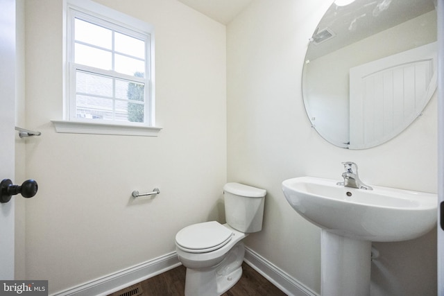 bathroom with toilet, visible vents, baseboards, and wood finished floors