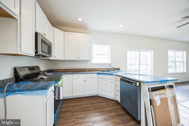 kitchen featuring dark wood-style flooring, a peninsula, stainless steel appliances, white cabinetry, and recessed lighting