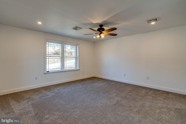 unfurnished room with dark carpet, visible vents, and baseboards