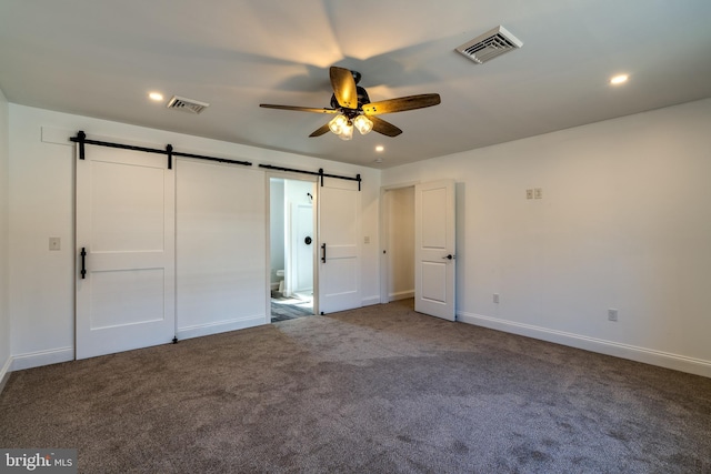 unfurnished bedroom with carpet, visible vents, recessed lighting, and a barn door