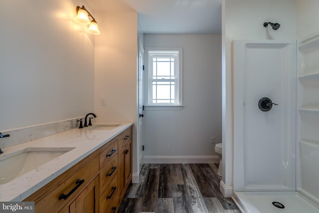 full bathroom with a sink, a shower stall, baseboards, and wood finished floors