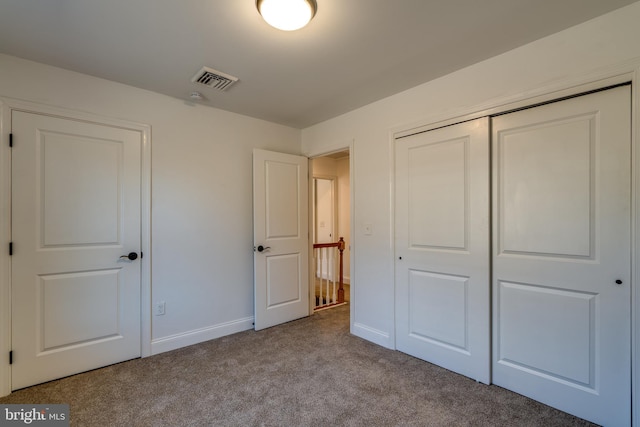 unfurnished bedroom featuring baseboards, carpet, visible vents, and a closet