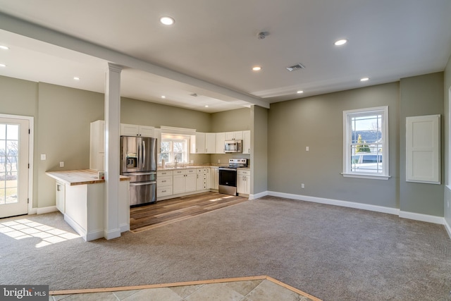 kitchen featuring recessed lighting, visible vents, stainless steel appliances, and light colored carpet