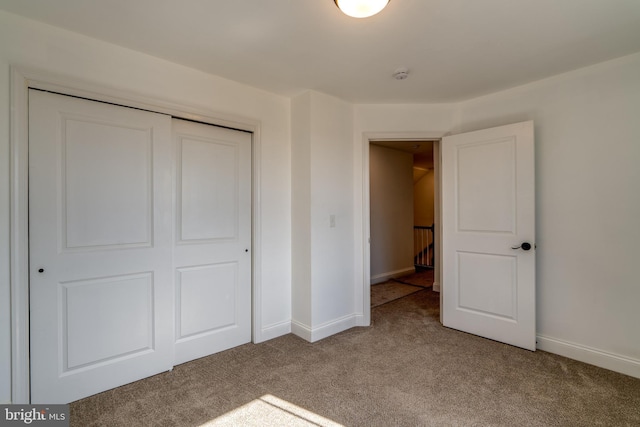 unfurnished bedroom featuring carpet floors, a closet, and baseboards