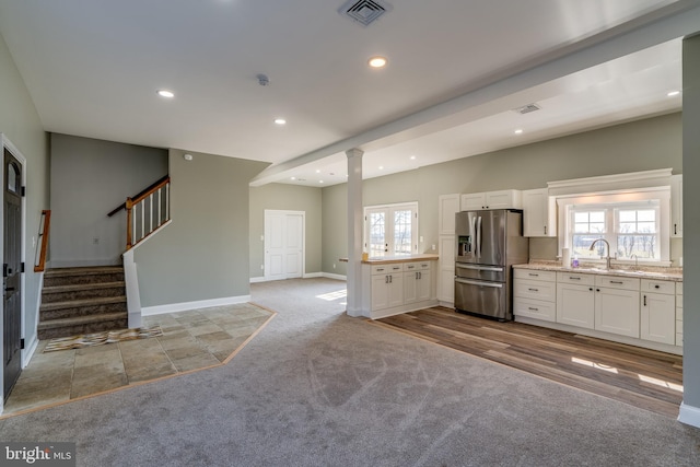 kitchen featuring visible vents, stainless steel fridge with ice dispenser, carpet flooring, white cabinetry, and a wealth of natural light