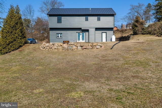 rear view of house with a standing seam roof, metal roof, and a lawn