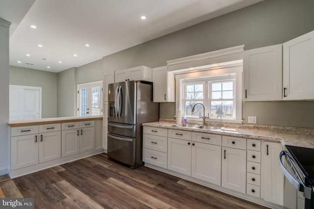 kitchen featuring recessed lighting, a sink, dark wood finished floors, white cabinets, and stainless steel fridge