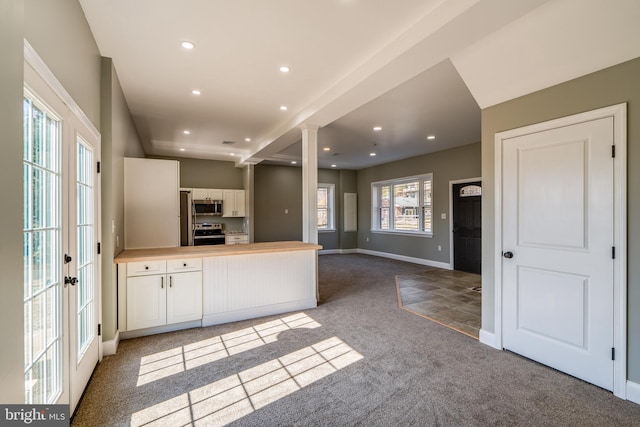 kitchen with appliances with stainless steel finishes, a peninsula, carpet floors, white cabinetry, and recessed lighting