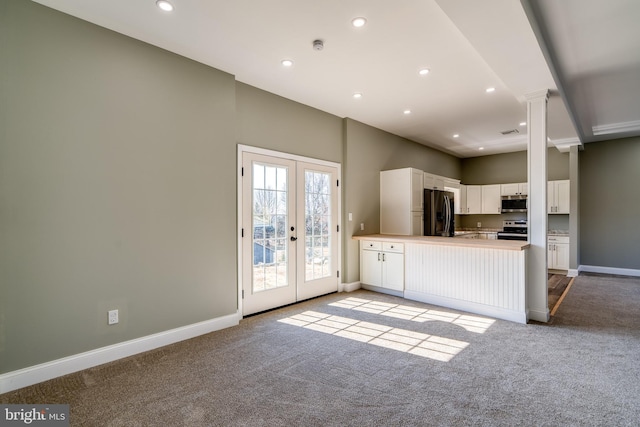 kitchen with stainless steel appliances, french doors, white cabinetry, and light colored carpet