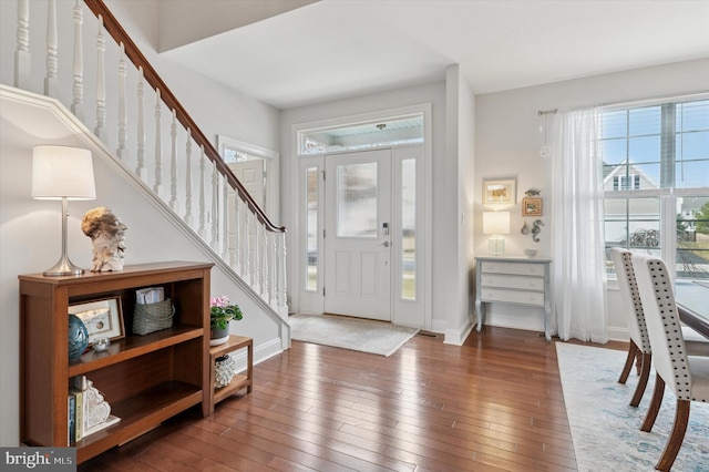 foyer entrance featuring wood-type flooring, stairway, and baseboards