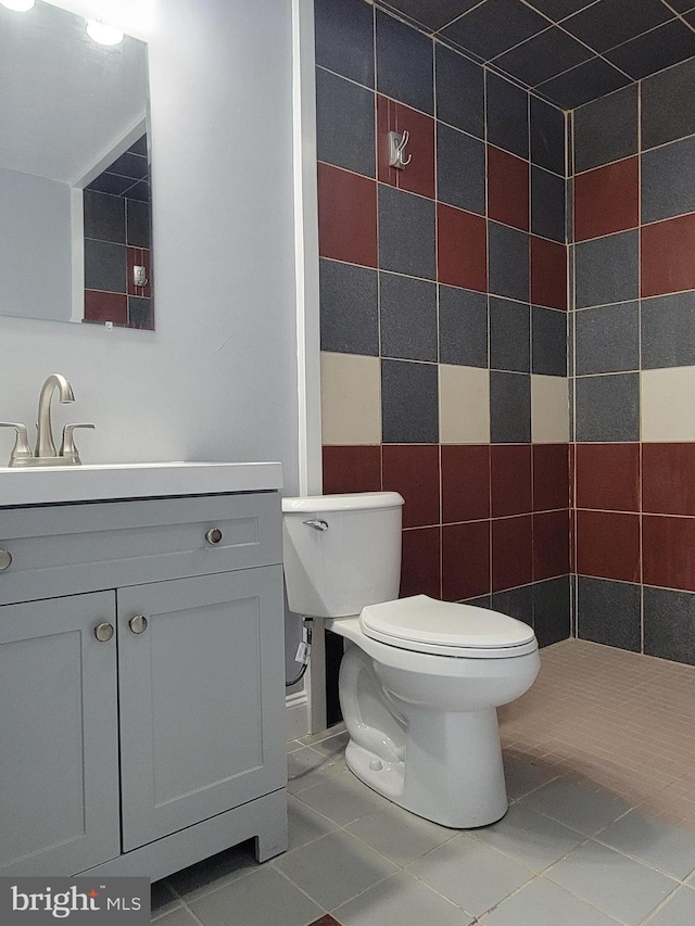 bathroom with tile patterned flooring, tile walls, toilet, and vanity