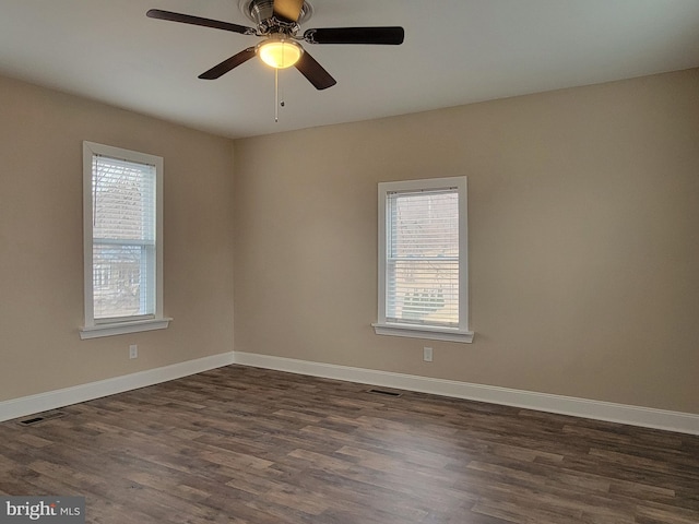 empty room featuring baseboards, visible vents, ceiling fan, and dark wood-style flooring